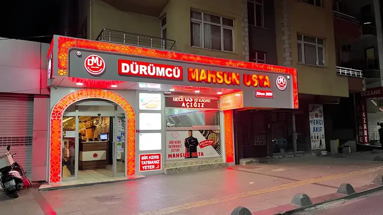 Dürümcü Mahsun Usta Güneşli şubesinin ışıklı cephesi; vitrinde "Gece 03'e kadar açığız" yazısı
